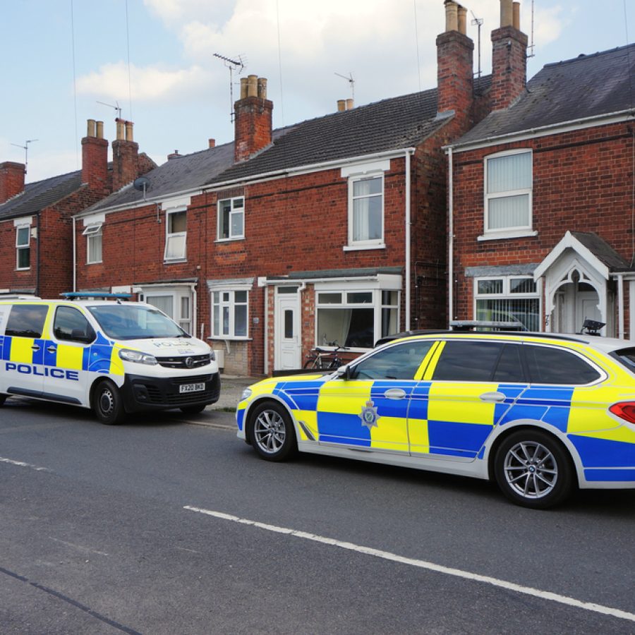 A,Police,Car,And,Van,Parked,Outside,A,Row,Of