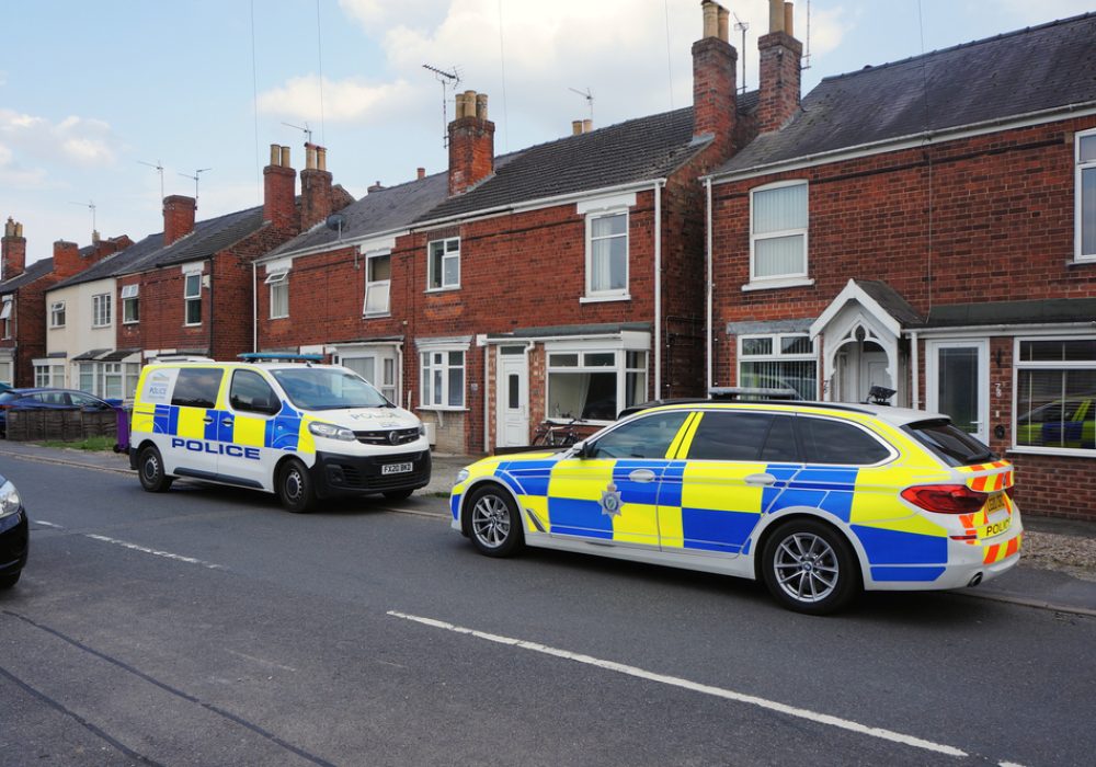 A,Police,Car,And,Van,Parked,Outside,A,Row,Of