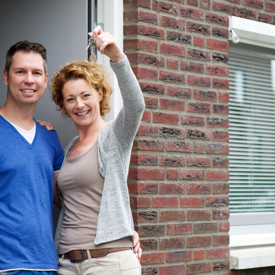 Portrait,Of,A,Couple,Smiling,And,Holding,Keys,To,Their