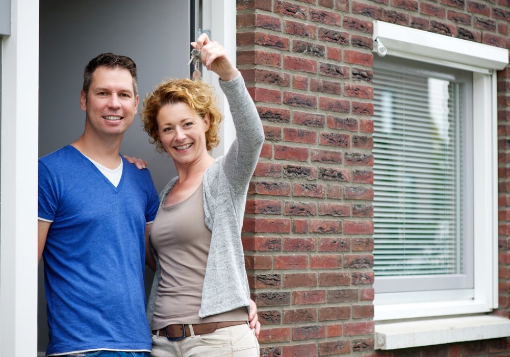 Portrait,Of,A,Couple,Smiling,And,Holding,Keys,To,Their