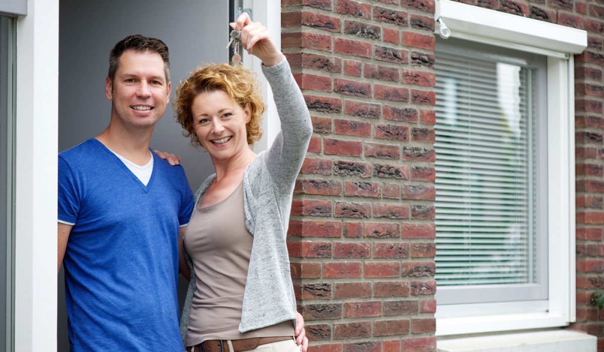 Portrait,Of,A,Couple,Smiling,And,Holding,Keys,To,Their