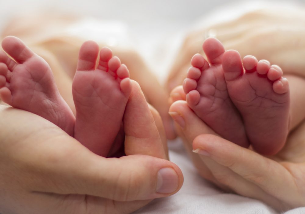 Mother,And,Father's,Hands,Cradling,Twin,Babies',Feet,On,A